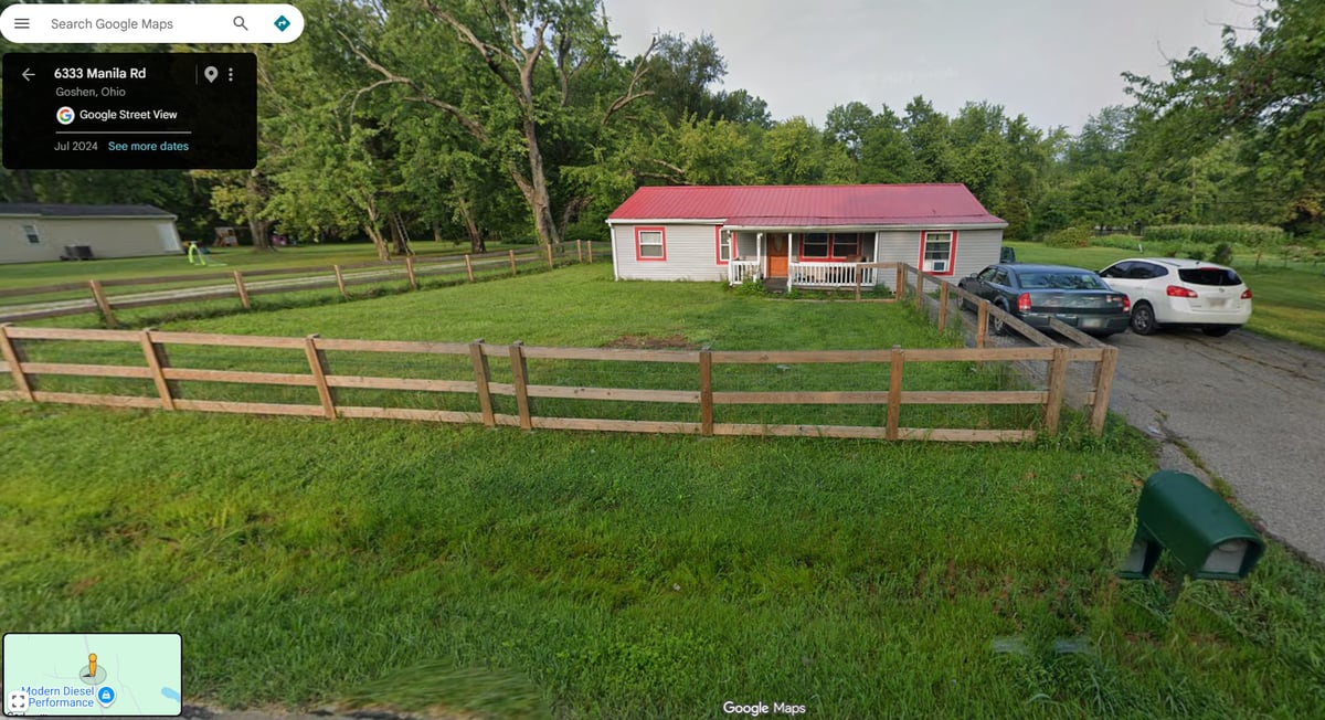 Aerial front view of 6333 Manila Rd — red roof ranch and pole barn on 0.82 acres